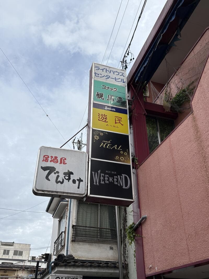 上田市中心部の外壁に突き出す「でぃす」「HEAL」「WEEKEND」などの縦並び看板