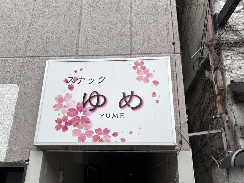 桜の意匠を散らした白い「スナック ゆめ」看板