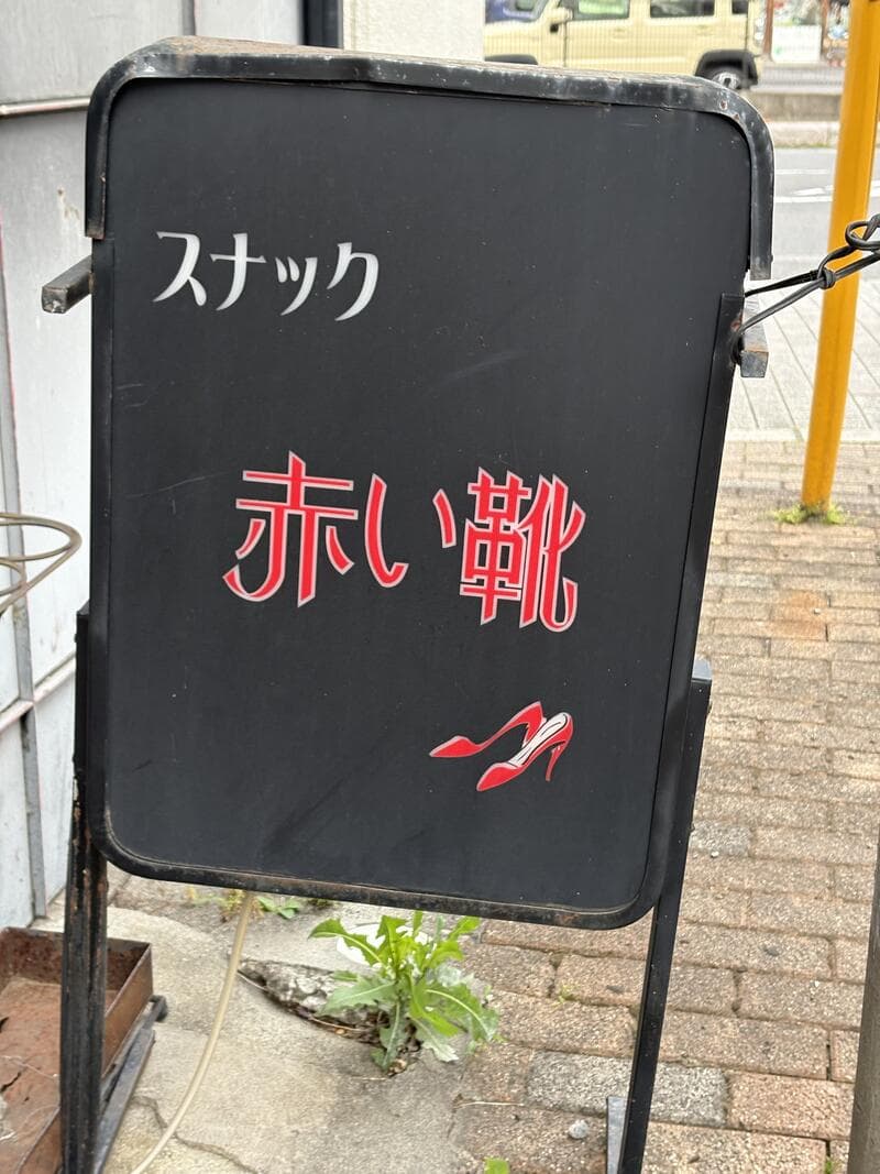 黒い置き看板に赤文字を浮かべた「スナック 赤い靴」