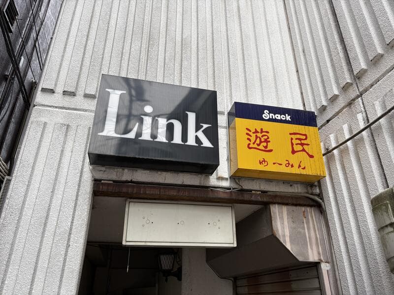 入口上に並ぶ黒い「Link」と黄色い「Snack 遊民」の看板