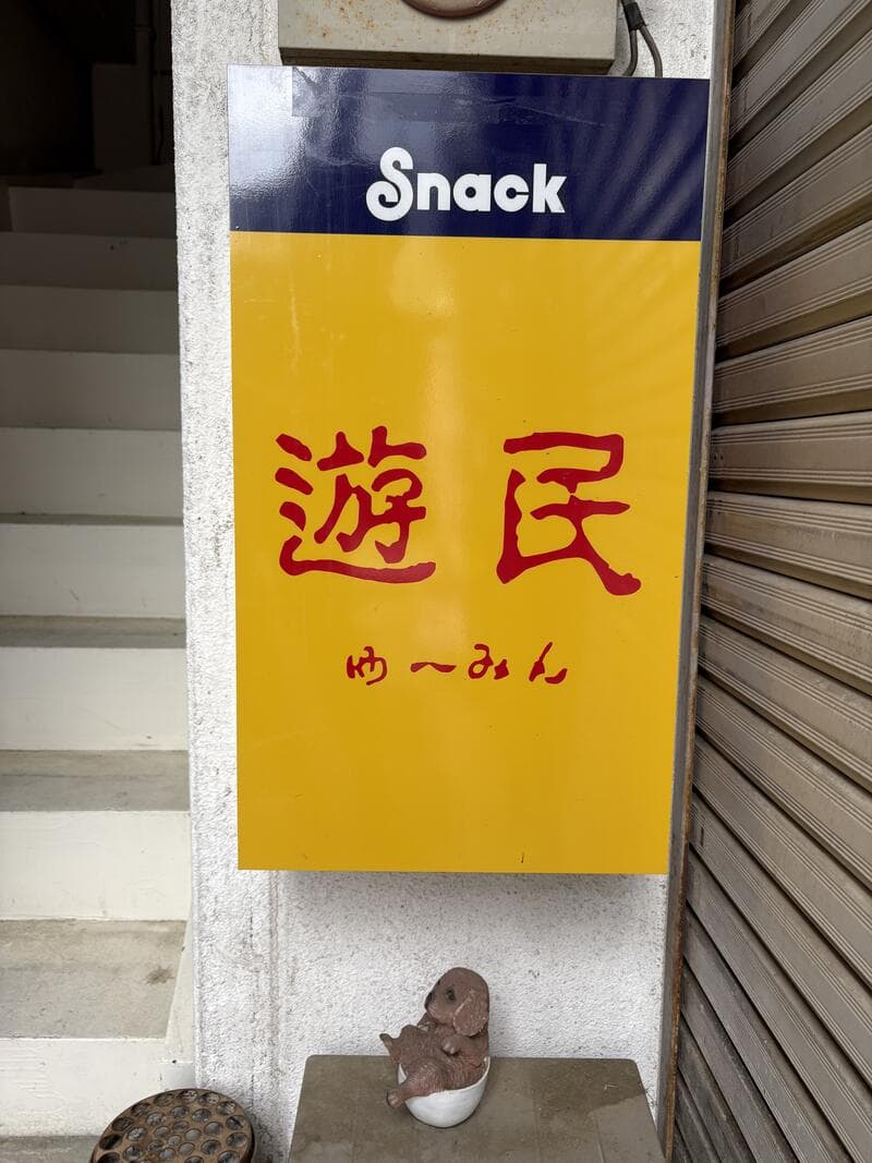 階段脇に掛けられた黄色い「Snack 遊民」看板