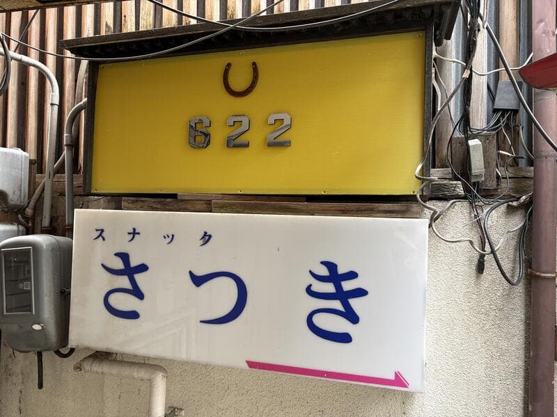 黄色い「822」と白い「スナック さつき」が重なる入口看板