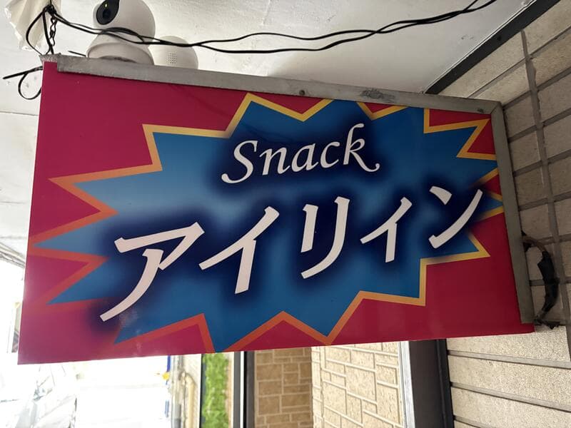 ピンク地に青い吹き出しを重ねた「Snack アイリィン」看板