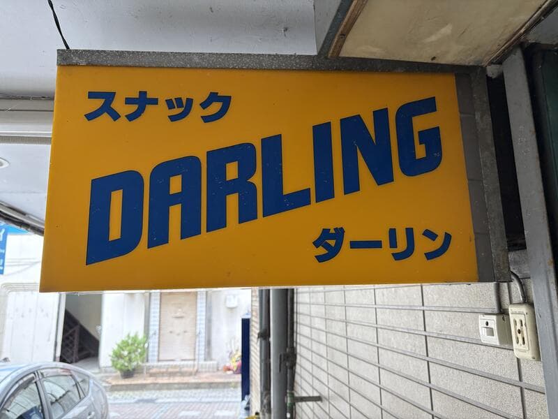 黄色地に青い斜体文字が走る「スナック DARLING」看板
