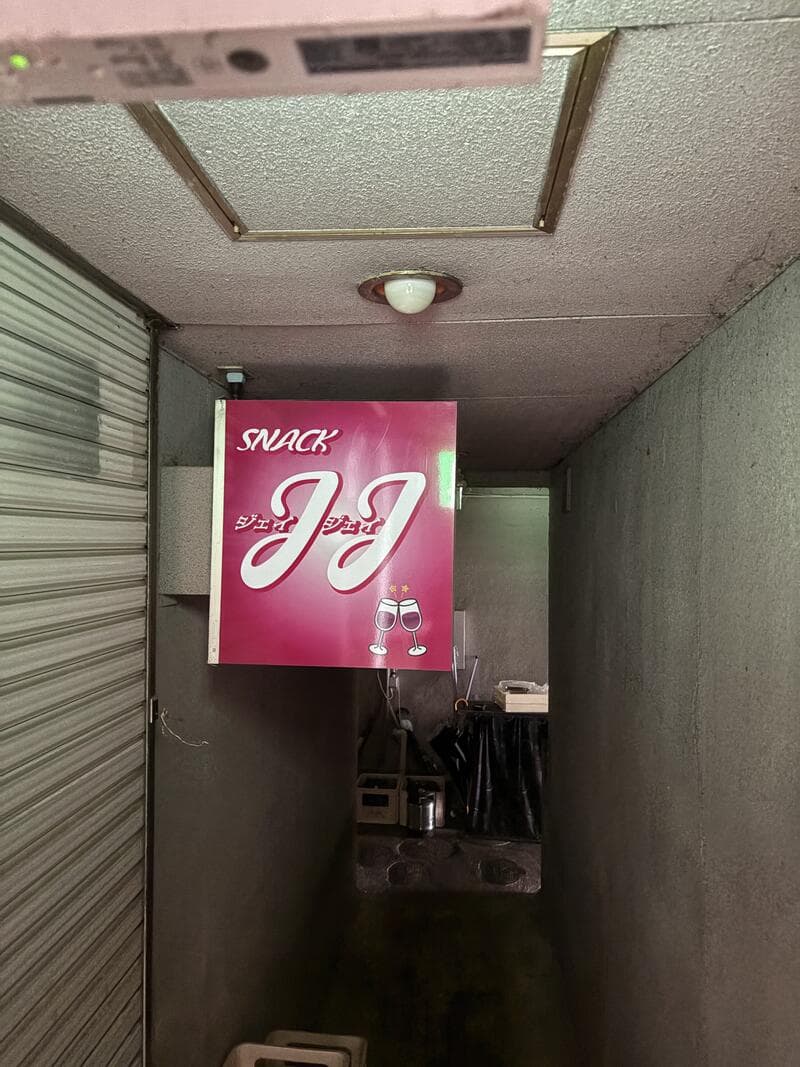 細い通路の奥に灯るピンクの「SNACK JJ」袖看板