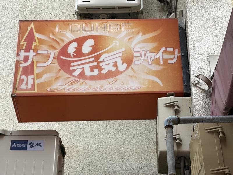オレンジ地に炎のような文字を置いた「サンシャイン 元気」看板