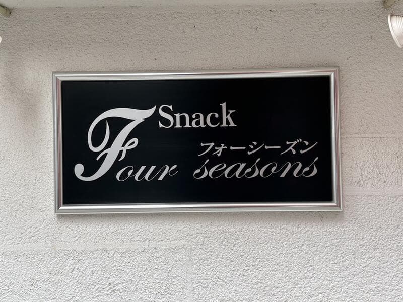黒地に白い筆記体を置いた「Snack Four Seasons」看板