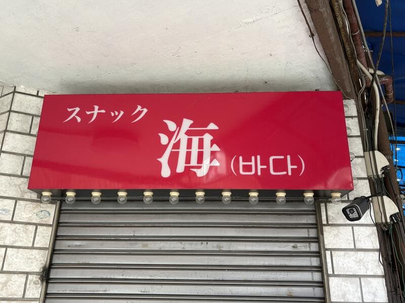 赤い面板に大きな白文字を置いた「スナック 海」看板