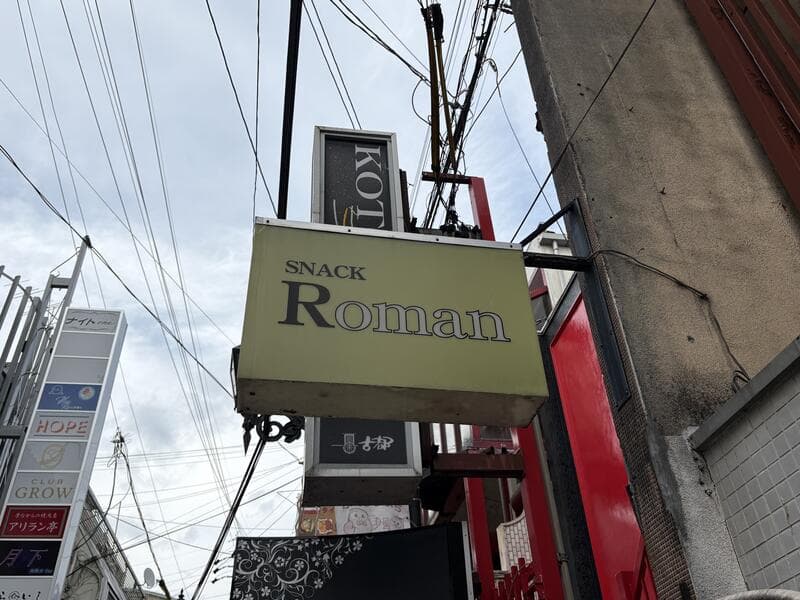 路地の上に重なる「Román」と「JOY」の袖看板