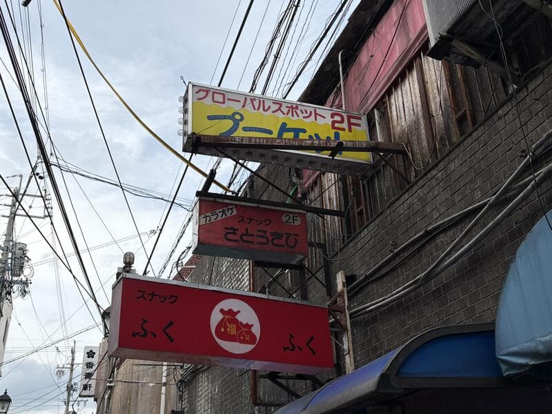 路地上に重なる「ブーメラン」「ふくふく」などの赤い看板群