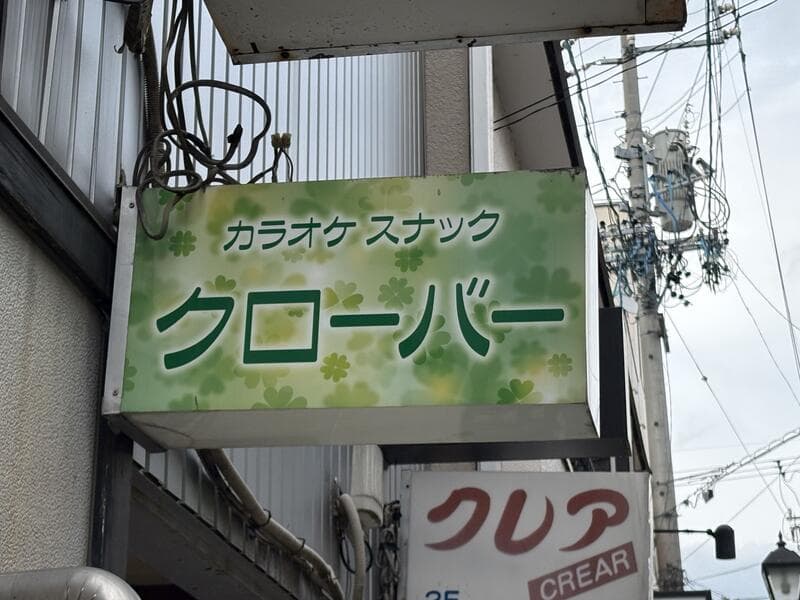 緑の柄地に大きく書かれた「カラオケ スナック クローバー」看板