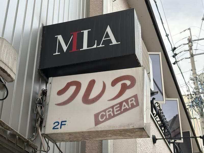 黒い「MILA」と白い「クレア CREAR」が上下に重なる2階看板