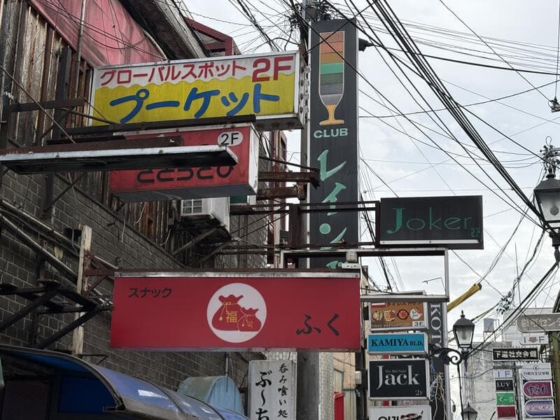 「ブーメラン」「ととろこ」「ふく」などが重なる路地の集合看板
