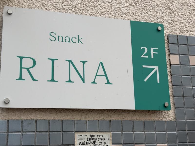 白地と緑帯で2階を示す「Snack RINA」看板