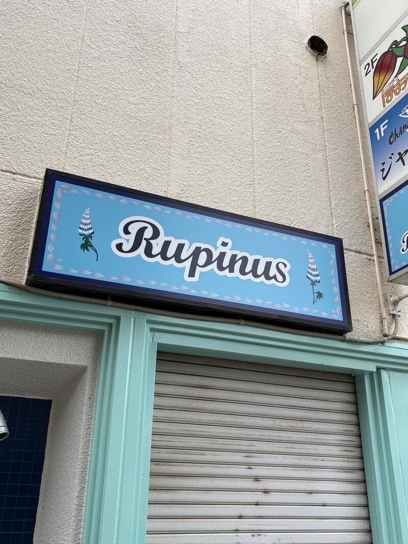 水色の外壁に掲げられた筆記体ロゴの「Rupinus」看板