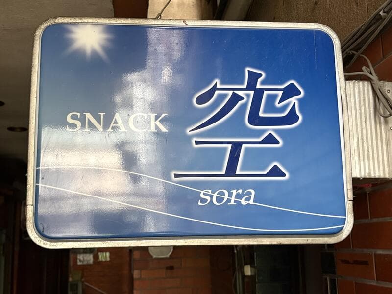 青空の写真を背景にした「SNACK 空 sora」看板