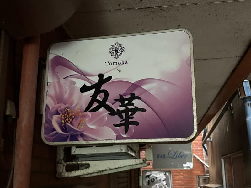 紫の花背景に筆文字を重ねた「友華 Tomoka」看板