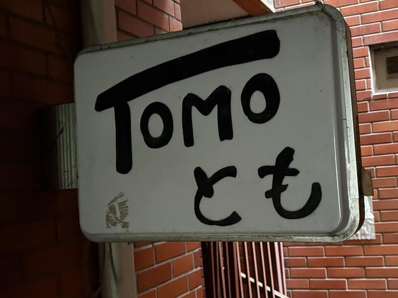 手書き風の黒文字が目立つ白い「TOMO とも」看板