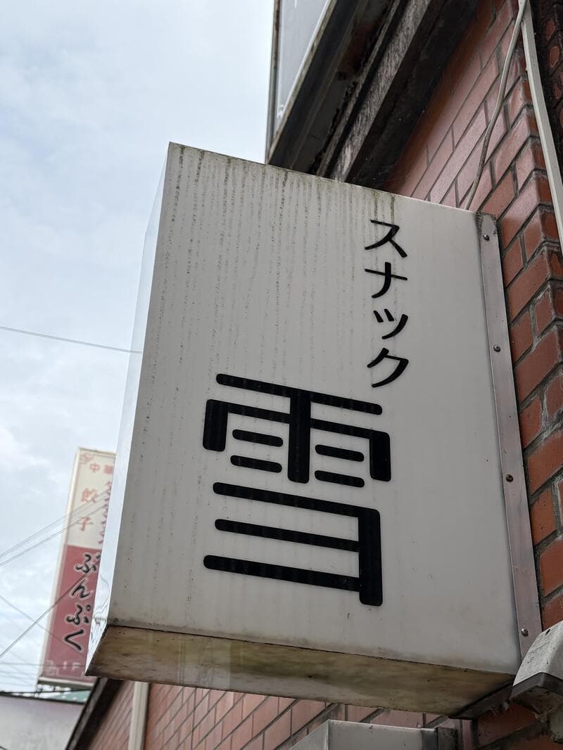 外壁に突き出す白い「スナック 雪」袖看板