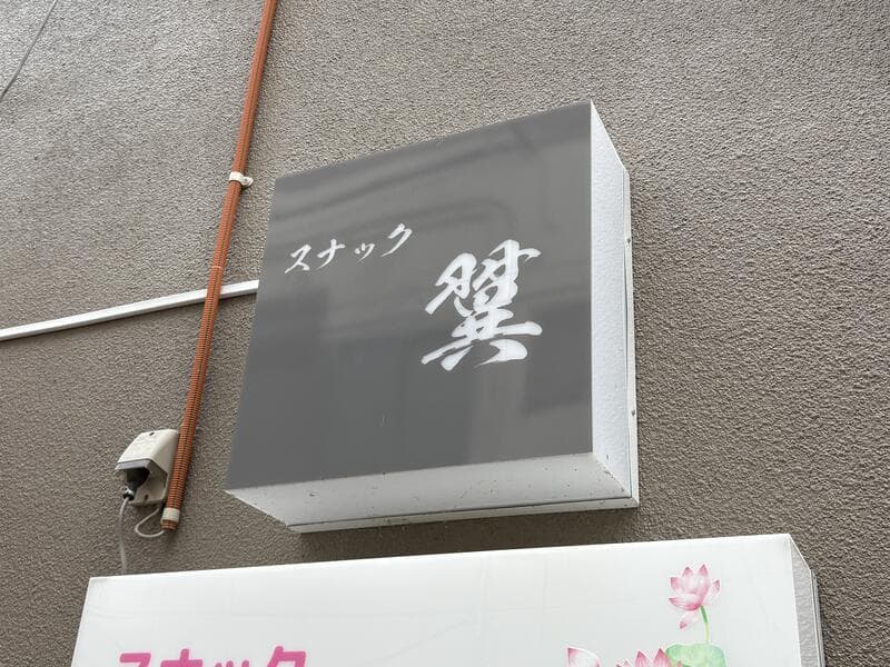 灰色の箱看板に白い筆文字を置いた「スナック 燈」看板