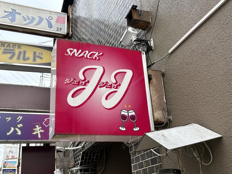 「JJ」「オッパ」「エメラルド」「ツバキ」が重なる路地の袖看板群