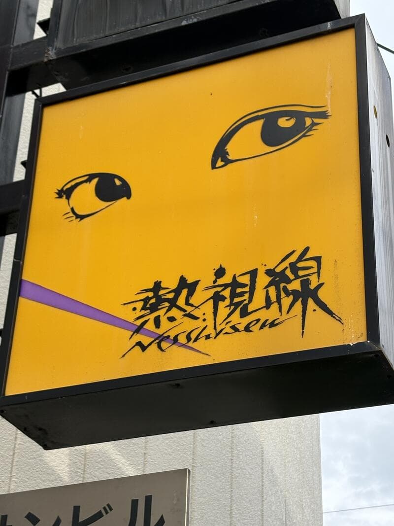 黄色い箱看板に目元のイラストを置いた「熱視線」看板