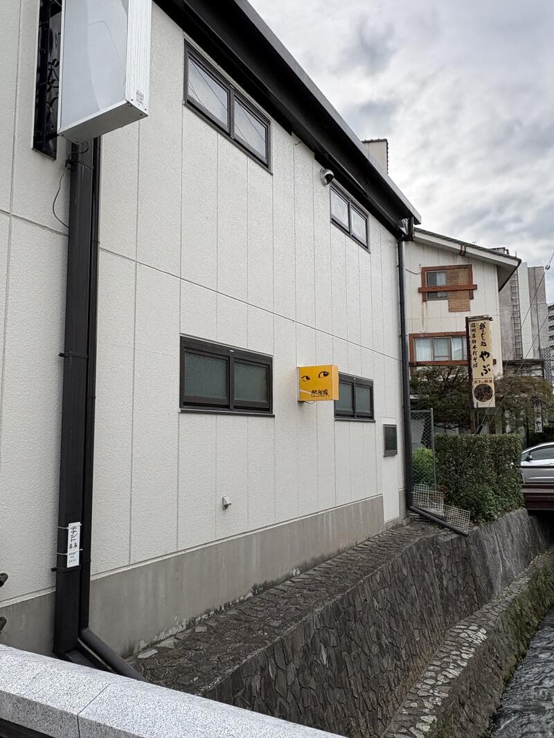 路地奥の白い外壁に小さく掛かる「熱視線」看板