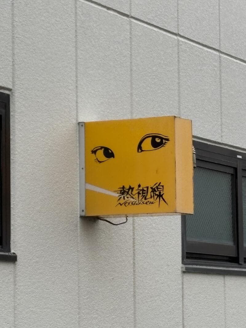 白壁に取り付けられた黄色い「熱視線」箱看板