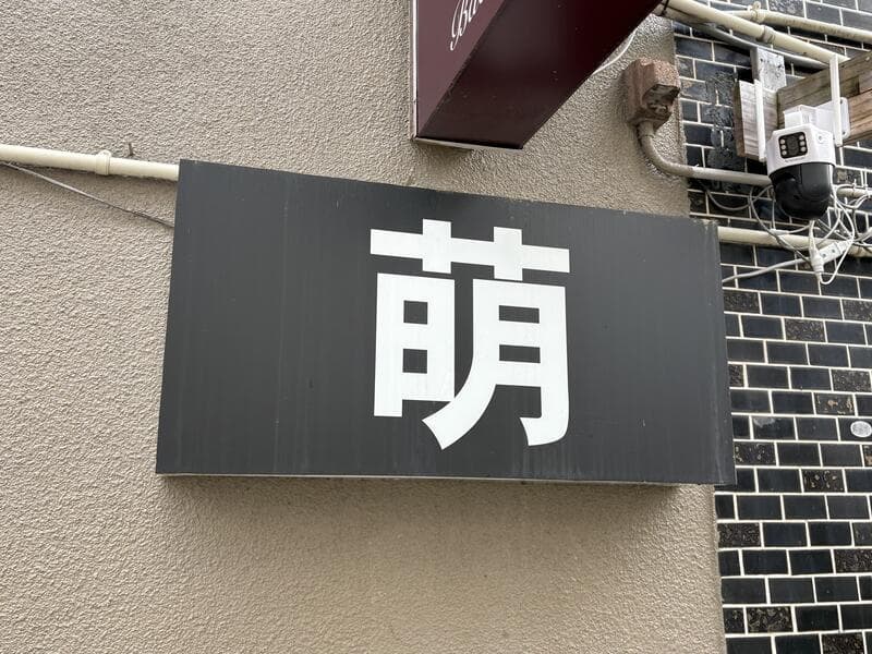 黒地に大きな白文字を置いた「萌」看板