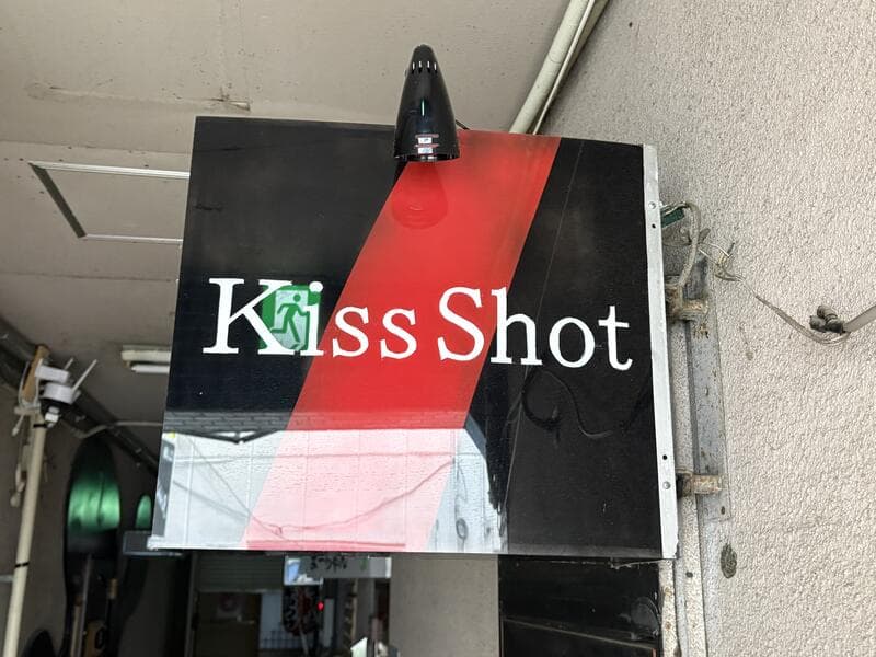 赤と黒の斜め構成が目立つ「Kiss Shot」看板
