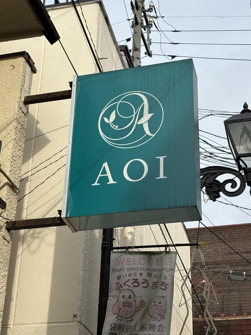 緑の箱看板に白いロゴを置いた「AOI」看板