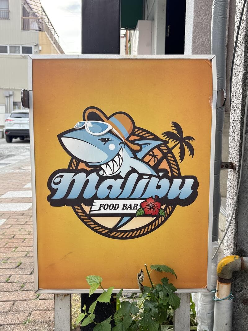 魚のキャラクターを大きく描いた黄色い「malibu SEAFOOD BAR」看板