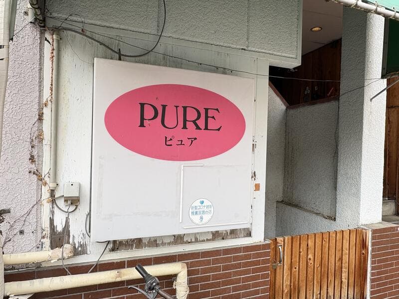 白地にピンク楕円を置いた「PURE ピュア」看板