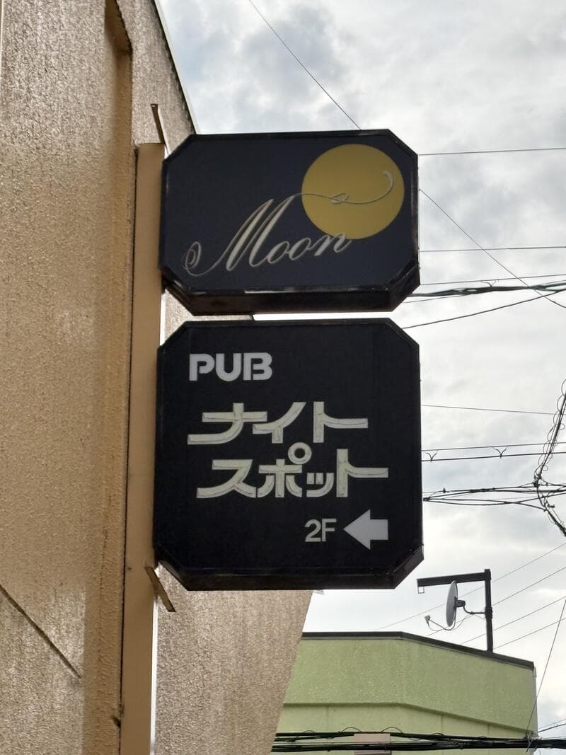 「Moon」と「PUB ナイトスポット」が上下に並ぶ黒い袖看板