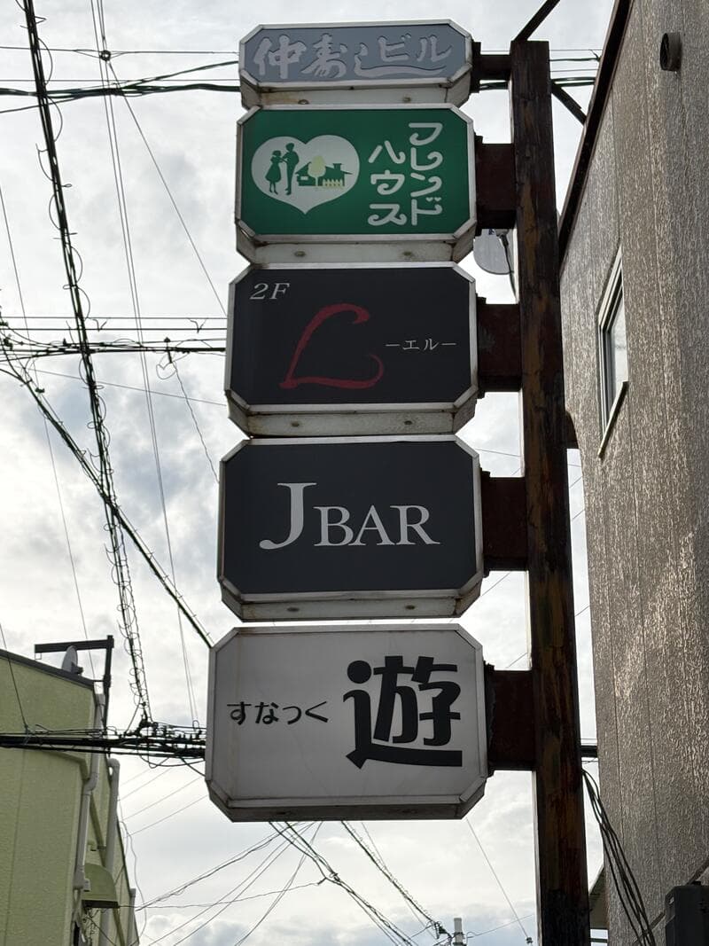 「フレンドハウス」「J BAR」「遊」が縦に重なる袖看板群