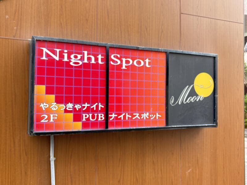 木目壁に掛かる赤黒の「Night Spot Moon」看板