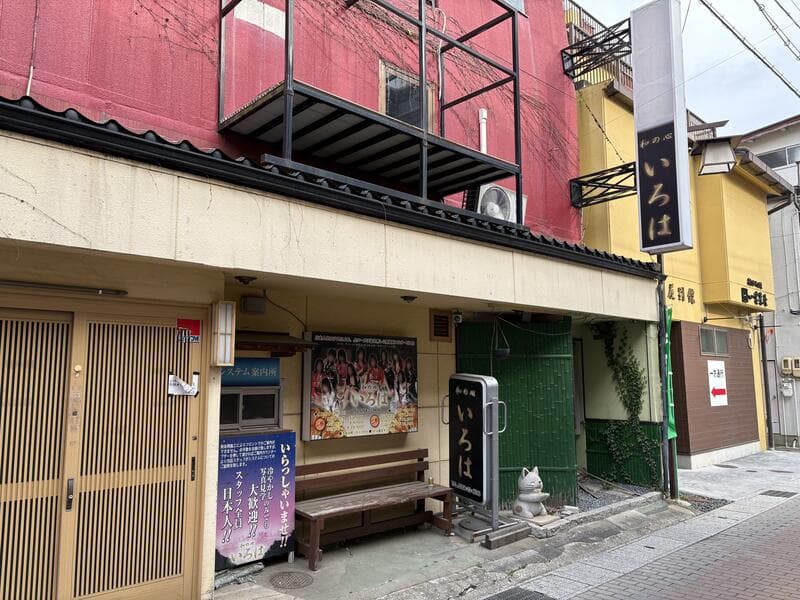 赤い建物の路地入口に見える複数の看板風景
