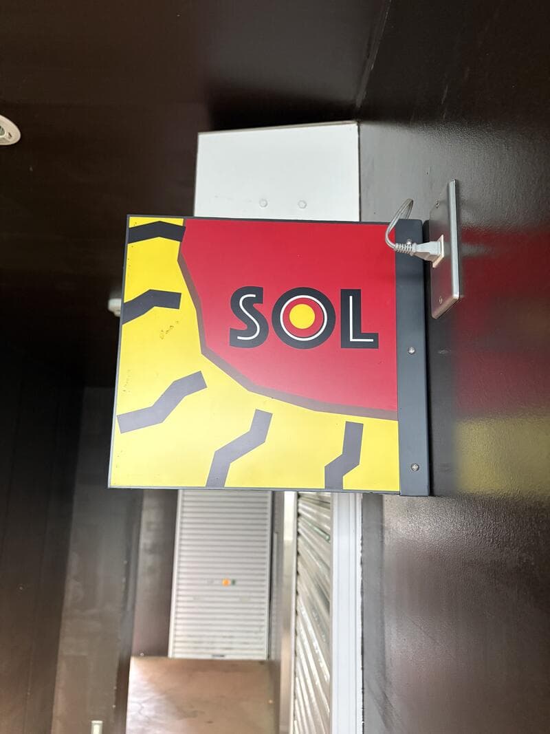 通路奥に見える赤黄黒の「SOL」看板