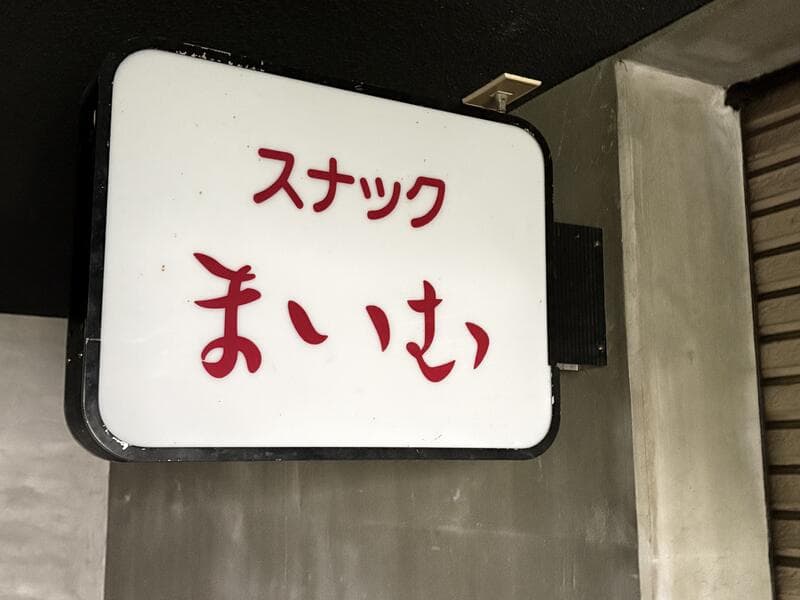 白地に赤文字の「スナック まいむ」看板