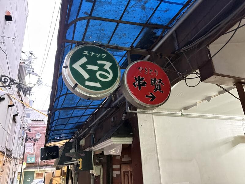 丸い「スナック くる」と「串賢」の袖看板