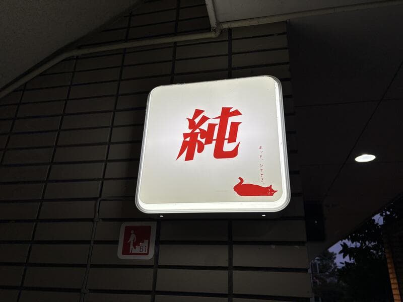 夜に灯る白地の「純」看板