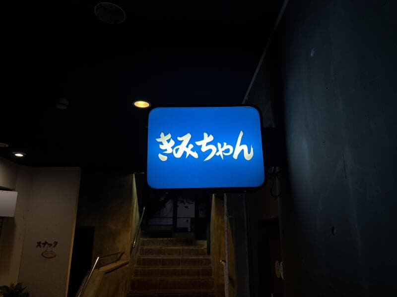 階段脇で青く光る「きみちゃん」看板