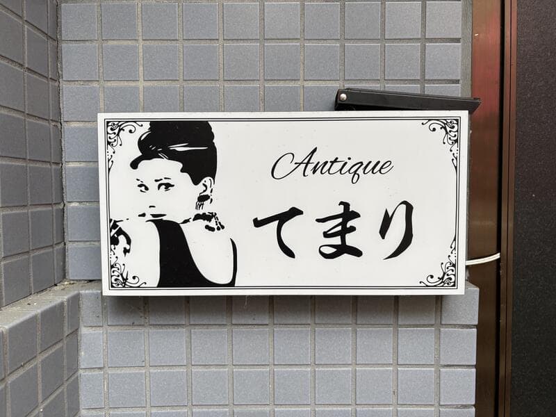 富山・桜木町の白い小プレートに残る「てまり」の横顔ロゴ
